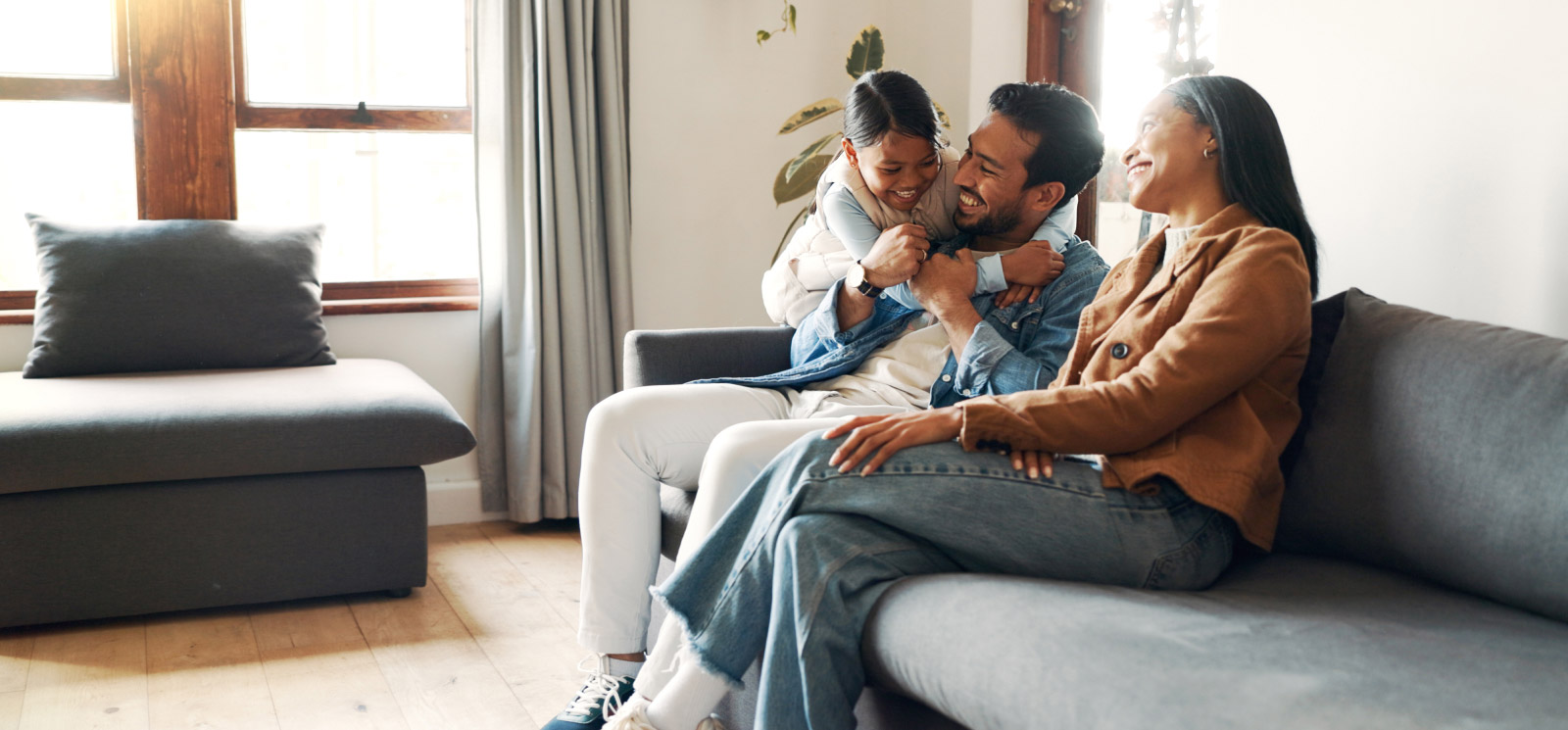 family at home sitting on the couch as they share smiles