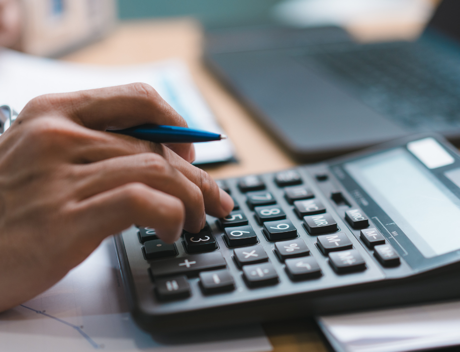 Close up of man's hand holding a pen and using a calculator with the same hand.